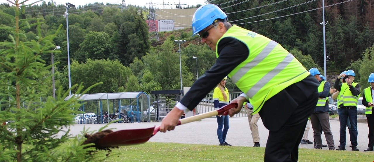 Mann med refleksvest og hjelm som graver hull for planting av tre