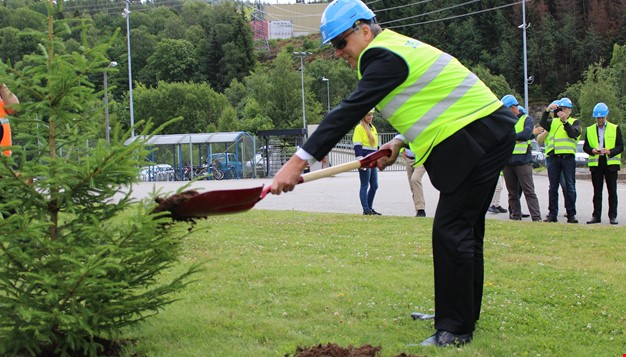 Mann med refleksvest og hjelm som graver hull for planting av tre