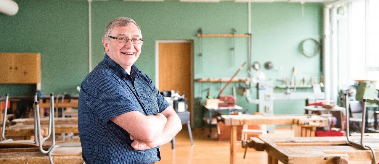 Mann som smiler mot kameraet inne på et verksted