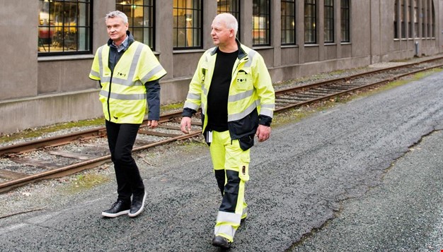 2 personer med refleks-kjeledress som vandrer ved siden av togskinne