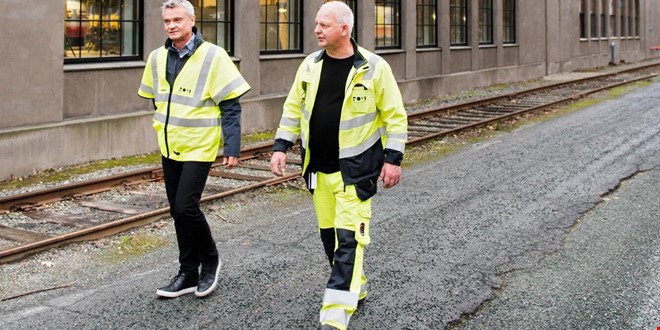 2 personer med refleks-kjeledress som vandrer ved siden av togskinne