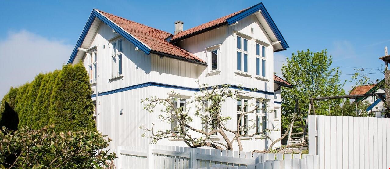 Hvit hus med hage og hekk