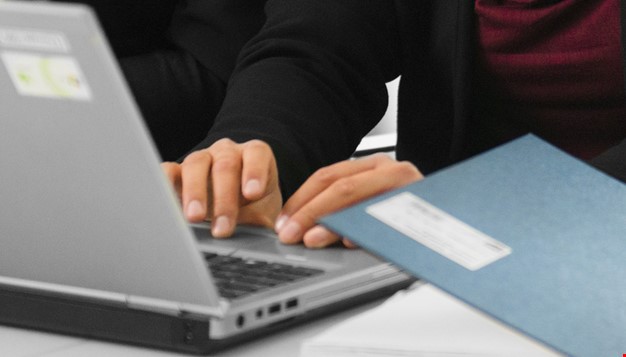 Hender som skriver på en laptop