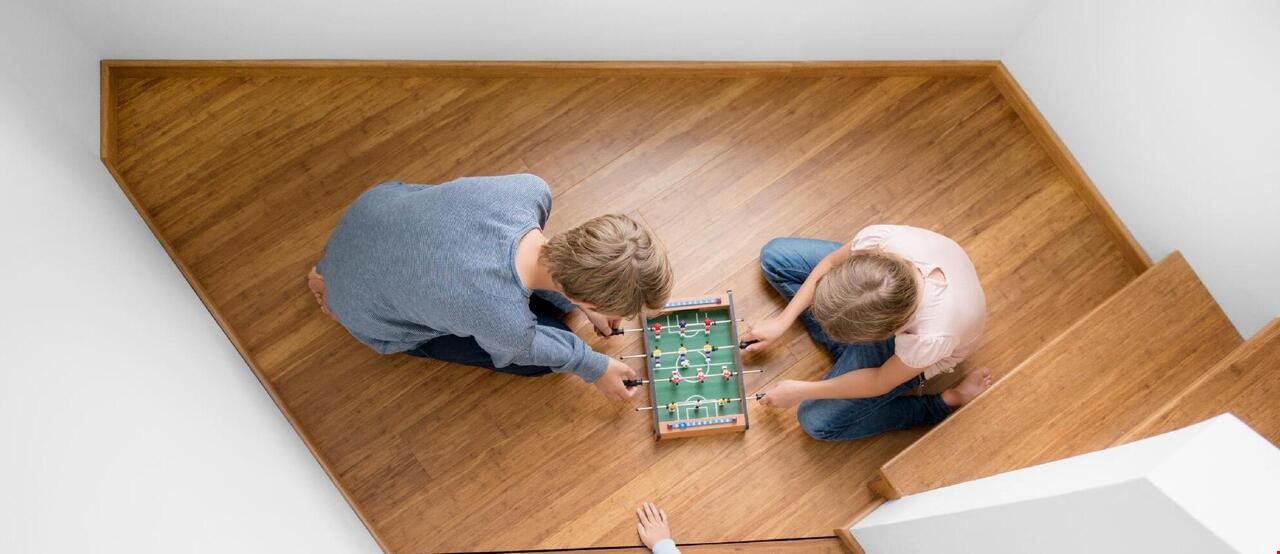 3 barn som sitter i på gulvet og spiller bordfotball