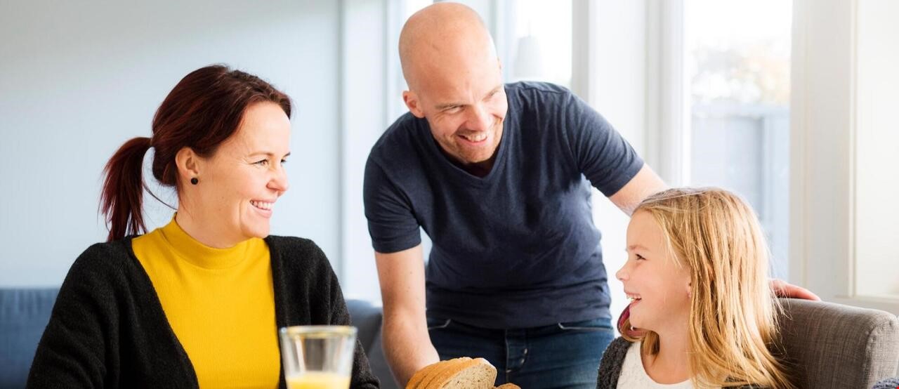 En famillie som smiler rundt frokostbordet