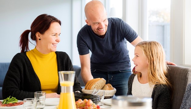 En famillie som smiler rundt frokostbordet