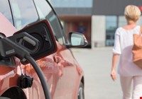 Person som går bort fra oransj bil som lader