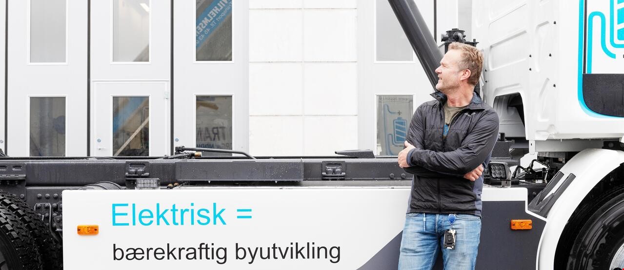 En mann står for foran en elektrisk lastebil med påskriften: Elektrisk = bærekraftig byutvikling