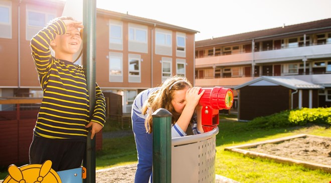 2 barn som leker på lekeplass utenfor leiligheter