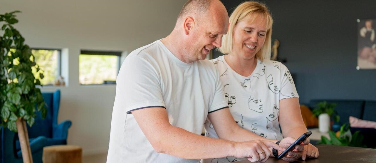 Mann og kvinne som smiler og ser på en telefon