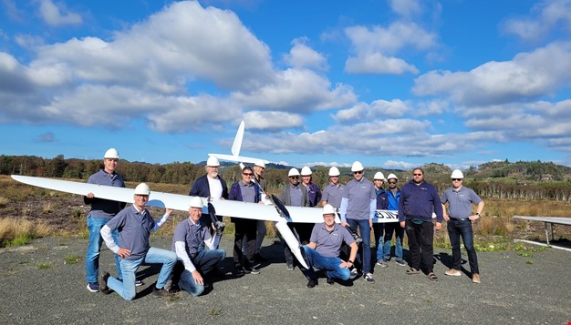 15 personer som holder et stort modellfly