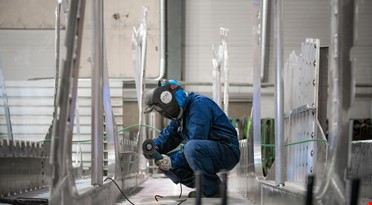 en mann som har på seg en maske og jobber på et stykke metall