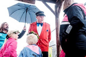 en mann i rød dress som holder en paraply og en blå sløyfe